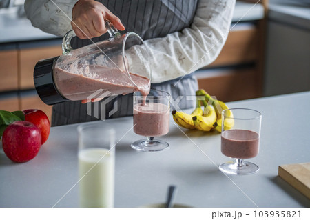 Woman preparing fresh fruit smoothie in the kitche Woman preparing fresh fruit smoothie in the kitche 103935821