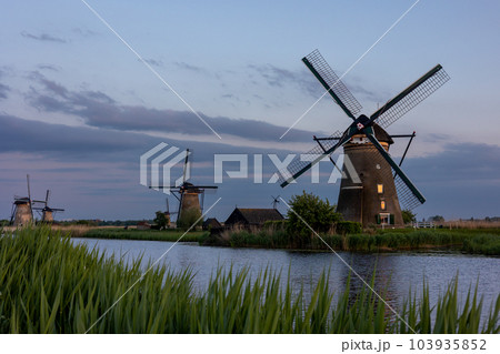 Beautiful wooden windmills at sunset in the Dutch village of Kinderdijk. Windmills run on the wind. The beautiful Dutch canals are filled with water. Beautiful sunset. Beautiful wooden windmills at sunset in the Dutch village of Kinderdijk. Windmills run on the wind. The beautiful Dutch canals are filled with water. Beautiful sunset. 103935852