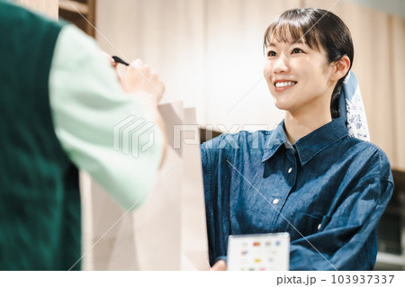 買い物客に紙袋を渡す女性店員 買い物客に紙袋を渡す女性店員 103937337