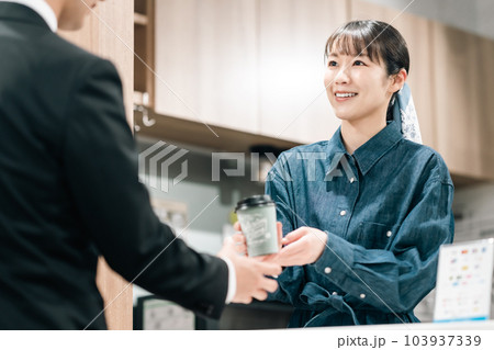 紙コップのコーヒーを手渡しする若い女性アルバイト 紙コップのコーヒーを手渡しする若い女性アルバイト 103937339