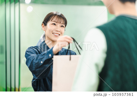 お店でお客様に商品を渡す女性店員 お店でお客様に商品を渡す女性店員 103937361