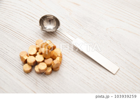 Sealing wax metal spoon, yellow golden sealing wax granules beads on wooden table. Top view Sealing wax metal spoon, yellow golden sealing wax granules beads on wooden table. Top view 103939259