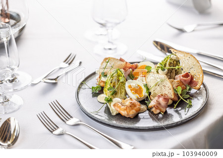 Luxury restaurant serves a modern twist on the classical ceasar salad on a dark plate 103940009