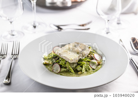 Restaurant serves cog fillet with green salad leaves and raddish in a deep plate Restaurant serves cog fillet with green salad leaves and raddish in a deep plate 103940020