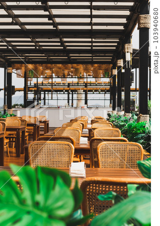 Wooden table and rattan chairs at open cafe outdoor. Wooden table and rattan chairs at open cafe outdoor. 103940680