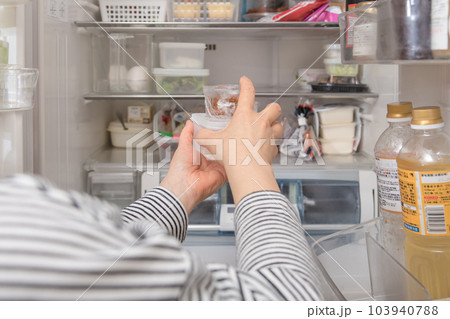 【冷蔵室からタッパを取り出す主婦】 103940788