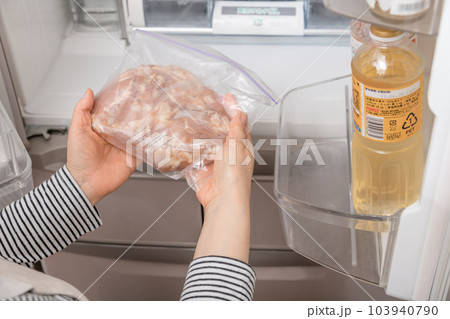【冷蔵室から唐揚用の下味を付けた鶏肉を出す主婦】 103940790