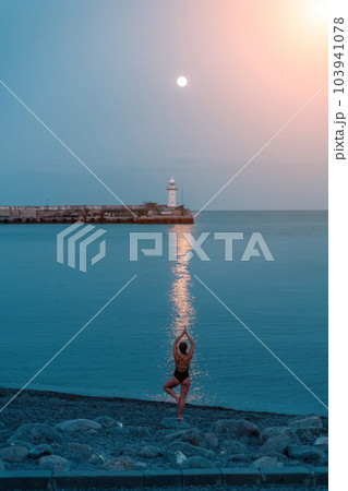 Woman The full moon rises to the lighthouse, the lunar path along the sea leads to the woman. 103941078