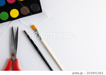 Close up of paints, paper, scissors and brushes with copy space on white background Close up of paints, paper, scissors and brushes with copy space on white background 103941361