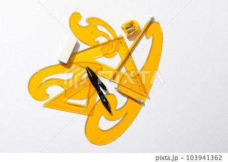 Close up of yellow rulers, compass and sharpener on white background Close up of yellow rulers, compass and sharpener on white background 103941362