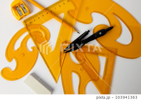 Close up of yellow rulers, compass and sharpener on white background Close up of yellow rulers, compass and sharpener on white background 103941363