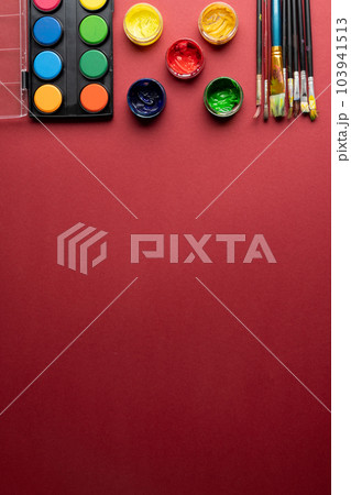 Close up of paints and brushes with copy space on red background 103941513
