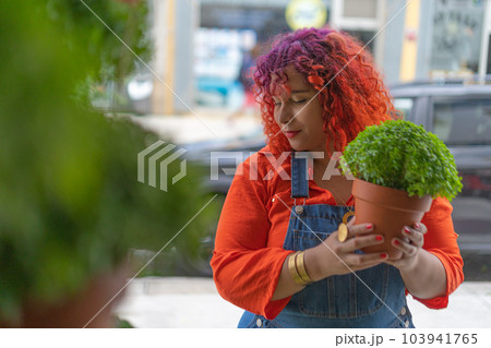 Young woman choosing manjerico plant in street shop Young woman choosing manjerico plant in street shop 103941765