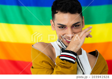 Portrait of happy biracial transgender man looking at camera with rainbow flag in background Portrait of happy biracial transgender man looking at camera with rainbow flag in background 103941928
