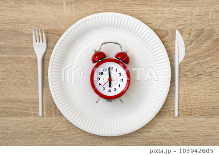 Concept of breakfast time with red alarm clock, disposable plate, fork, knife Concept of breakfast time with red alarm clock, disposable plate, fork, knife 103942605