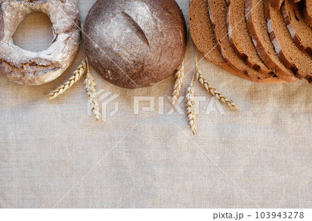 Baked bread. Loaf of Bread. Fresh Bakery Products on Wooden Board. Healthy Food Concept. Top View. Flat lay. Slices of Homemade Sourdough Bread with Flour on Rustic Linen Background. Wheat Spikes 103943278