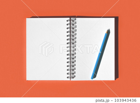 Notebook with pencil. School notebook on red orange background, spiral notepad on table. Top view of open notebook with blank pages, office notepad flat lay. Two white Pages for your write 103943436