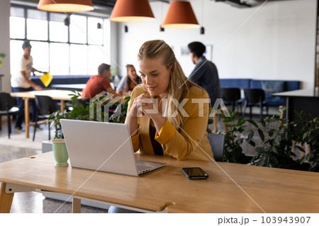 Happy plus size caucasian casual businesswoman making video call using laptop at desk Happy plus size caucasian casual businesswoman making video call using laptop at desk 103943907