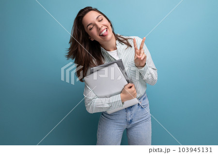 brunette young business woman in shirt with documents and laptop against background with copy pace brunette young business woman in shirt with documents and laptop against background with copy pace 103945131