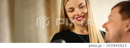 Man shows hair stylist to woman on phone Man shows hair stylist to woman on phone 103945823