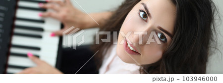 Portrait of happy woman looking up and playing synthesizer Portrait of happy woman looking up and playing synthesizer 103946000