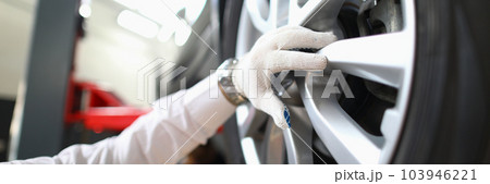 Mechanic changes car wheel in auto repair shop 103946221