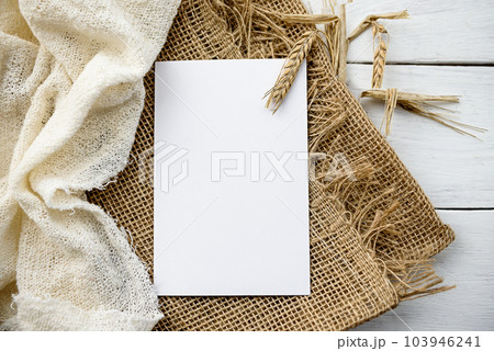 Stock stationery mock-up scene in a light key. Empty vertical greeting card and dried grains on white linen background. Stock stationery mock-up scene in a light key. Empty vertical greeting card and dried grains on white linen background. 103946241