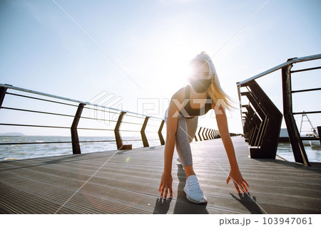 Young woman in protective mask. Sport woman doing stretching exercise near the sea. Sport, Active life. Young woman in protective mask. Sport woman doing stretching exercise near the sea. Sport, Active life. 103947061