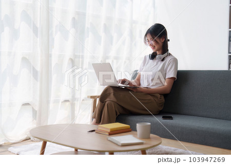 Young relaxed smiling pretty woman relaxing sitting on sofa at home. Female feeling joy enjoying with laptop on cozy couch Young relaxed smiling pretty woman relaxing sitting on sofa at home. Female feeling joy enjoying with laptop on cozy couch 103947269