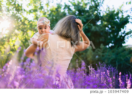 Mom with baby outdoor with lavender flowers and sunshine Mom with baby outdoor with lavender flowers and sunshine 103947409