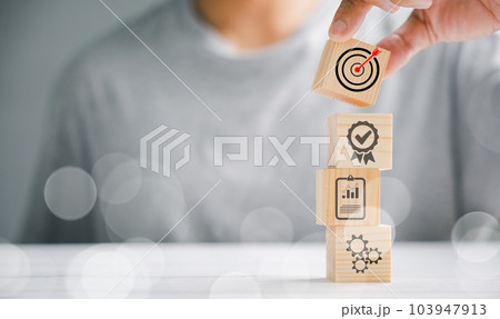 Wood block cube held by hand, showcasing the icon of company strategy development. Conceptual representation of success and business goals. Wood block cube held by hand, showcasing the icon of company strategy development. Conceptual representation of success and business goals. 103947913