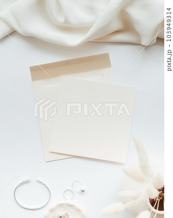 White blank paper sheet card mockup, envelope and floral branch in vase and silver jewelry on white background. White blank paper sheet card mockup, envelope and floral branch in vase and silver jewelry on white background. 103949314