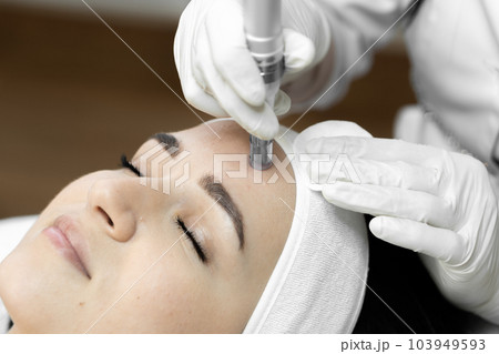 The photo conveys the moment of fractional mesotherapy, emphasizing the professionalism and experience cosmetologist in beauty clinic. Beautiful close-up girl at reception at doctor cosmetologist 103949593