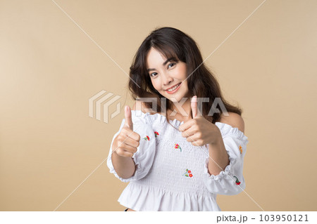 Young Asian woman showing two hands with thumbs up on isolated brown background 103950121