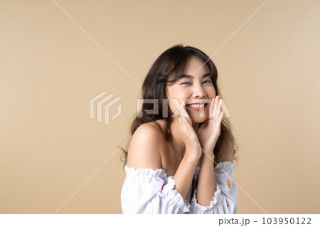Young Asian woman doing a shocked surprise gesture shouting with hands cupped around mouth isolated brown color background 103950122