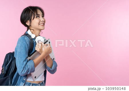 Portrait of smiling young Asian college student look to the side of the empty space with laptop and backpack isolated over pink background Portrait of smiling young Asian college student look to the side of the empty space with laptop and backpack isolated over pink background 103950148