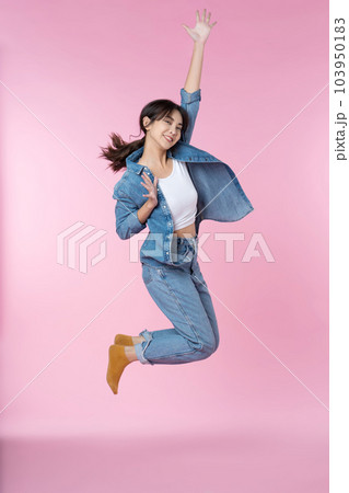 Elegant young Asian woman raises her arm and leg in a studio shot, expressing happiness and success isolated pink background Elegant young Asian woman raises her arm and leg in a studio shot, expressing happiness and success isolated pink background 103950183
