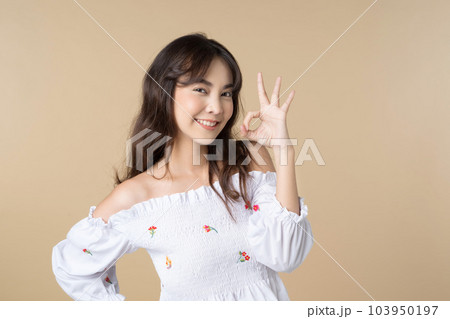 Young Asian woman showing ok sign on hand isolated brown color background 103950197