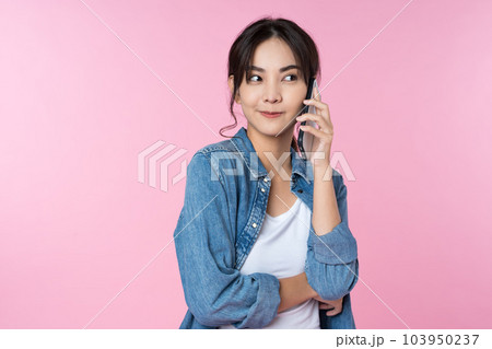 Young Asian woman talking on the phone holds cellphone making answering call on isolated pink background Young Asian woman talking on the phone holds cellphone making answering call on isolated pink background 103950237
