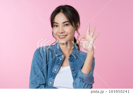 Young Asian woman showing ok sign on hand isolated pink color background 103950241