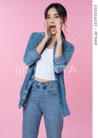 Young Asian woman doing a shocked surprise gesture shouting with hands cupped around mouth isolated pink color background 103950303