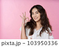 Young Asian woman showing ok sign on hand isolated pink color background 103950336