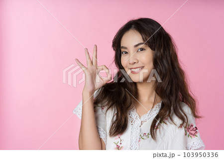 Young Asian woman showing ok sign on hand isolated pink color background 103950336