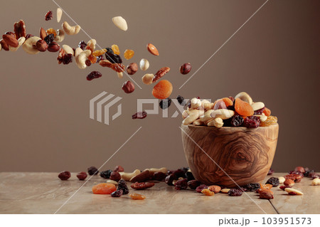 The mix of nuts and raisins in a wooden bowl. 103951573