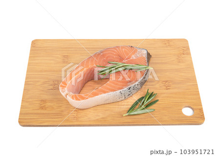 Portion steak from red fish, salmon, trout, on a cutting board with rosemary sprigs. 103951721
