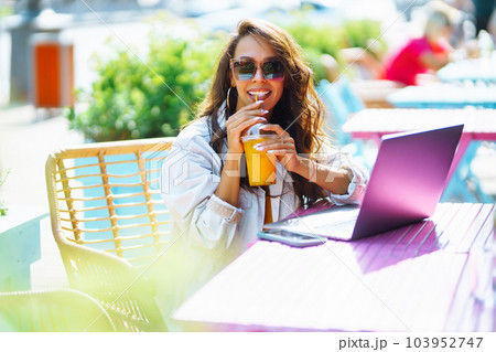 Portrait of happy young woman with a laptop at cafe. Freelancer working on a laptop. Business online Portrait of happy young woman with a laptop at cafe. Freelancer working on a laptop. Business online 103952747