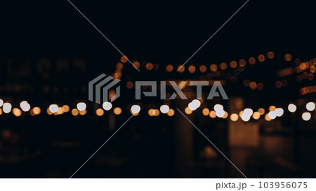 Decorative outdoor string lights at night time, Defocused Background, night city life backdrop, party time with Yellow bokeh balls 103956075
