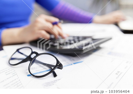 Woman using calculator for calculate domestic bills at home 103956404