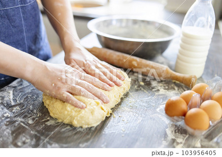 Female hands making dough for baking on wooden table Female hands making dough for baking on wooden table 103956405