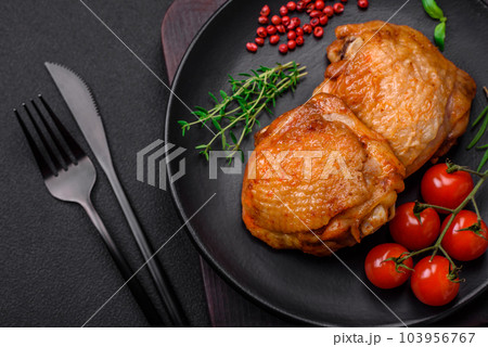 Delicious juicy chicken thighs baked with salt, spices and herbs in a ceramic plate 103956767
